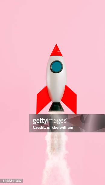 small space ship launches and flys up in the air on pink background - first space shuttle launch stock pictures, royalty-free photos & images