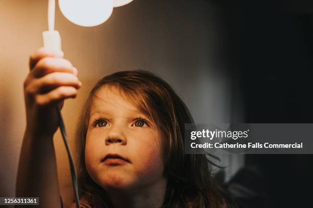little girl turning on a light - schakelaar stockfoto's en -beelden