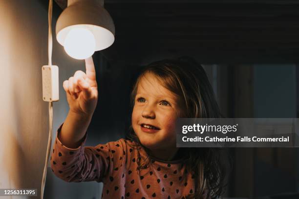 little girl pointing at a light - encender o apagar fotografías e imágenes de stock