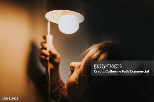 little girl turning on a light - encender o apagar fotografías e imágenes de stock