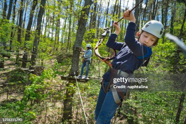 junge überwindet hindernisse im adventure rope park - baumkrone stock-fotos und bilder