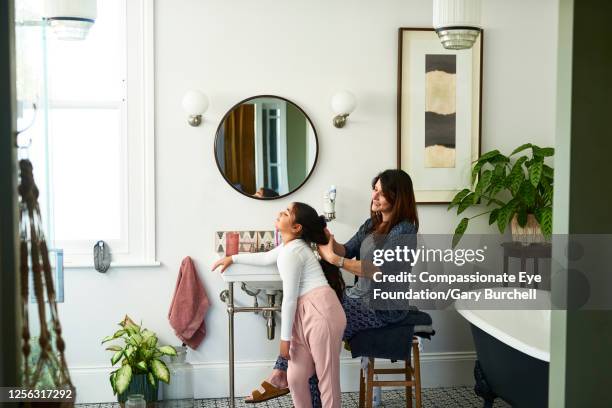 mother brushing daughter's hair in bathroom - bathroom pot plant stock pictures, royalty-free photos & images