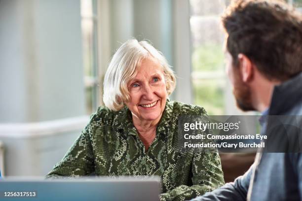 senior woman meeting with financial consultant at home - doing a favor - fotografias e filmes do acervo