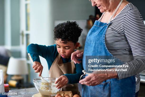 grandmother and grandson baking cupcakes - kitchen apron stock pictures, royalty-free photos & images