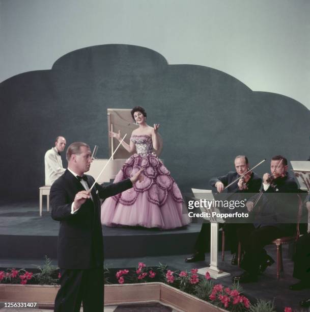 English singer Alma Cogan performs on stage with conductor Eric Winstone and his orchestra in England in 1955.
