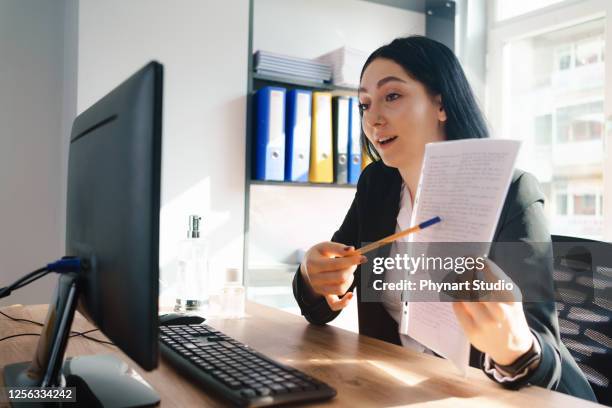 happy executive pointing contract on videocall at office - women talking in a bank with computer stock pictures, royalty-free photos & images