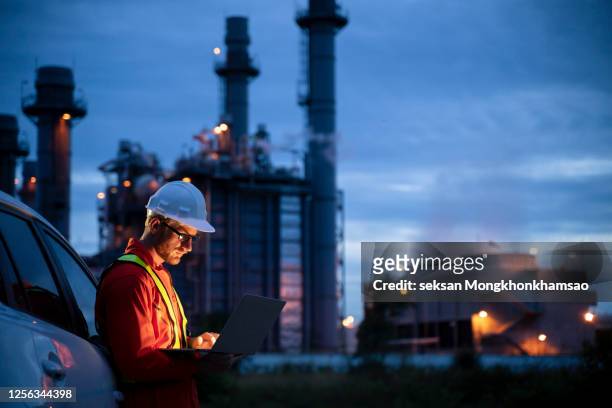 petrochemical engineers work slowly and heavily with smart tablets in the oil and gas industry at night. - energie industrie stockfoto's en -beelden