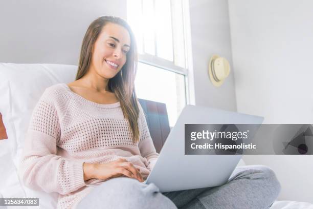 woman working at home in bed during the covid-19 quarantine - woman jogging pants stock pictures, royalty-free photos & images