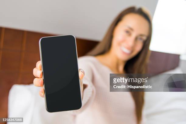 woman at home using app on her cell phone and showing the screen to the camera - showing stock pictures, royalty-free photos & images