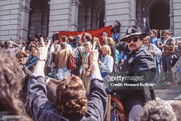 Elevated view over anti-Klan demonstrators, and one mounted police officer, outside the Colorado State Capitol Building, on the steps of which a...