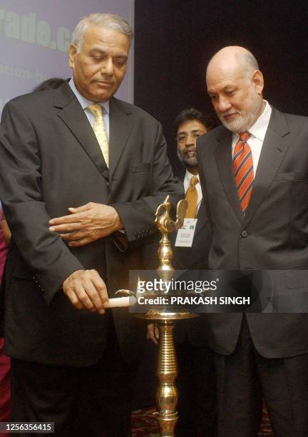 India's External Affairs Minister Yashwant Sinha lights a lamp as Pakistan's High Commissioner to India Aziz Ahmed Khan looks on during the...