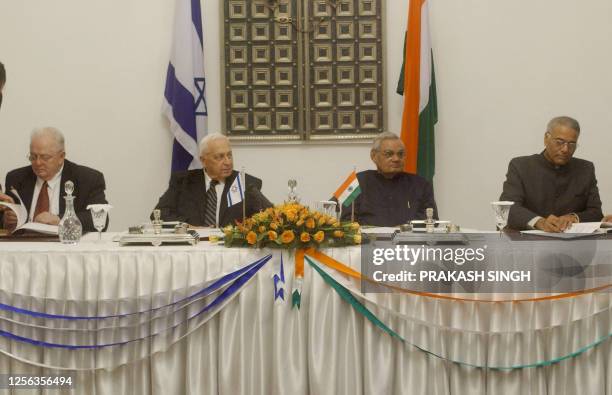 Israel's Deputy Prime Minister Yosef Lapid and Indian Foreign Minister Yashwant Sinha sign agreement documents as Israel's Prime Minister Ariel...