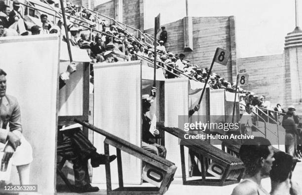 The judges declare their scores from individual booths during the diving events of the 1936 Summer Olympics, held at the Berlin Olympic Swim Stadium...
