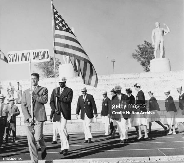 American decathlete Rafer Johnson is the flag bearer leading the United States Olympic team as they leave the Stadium of the Marbles on their way to...