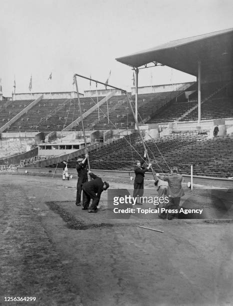Workers dismantle the trapeze bar following the postponement of the gymnastics events of the 1948 Summer Olympics, after heavy rain had fallen and...