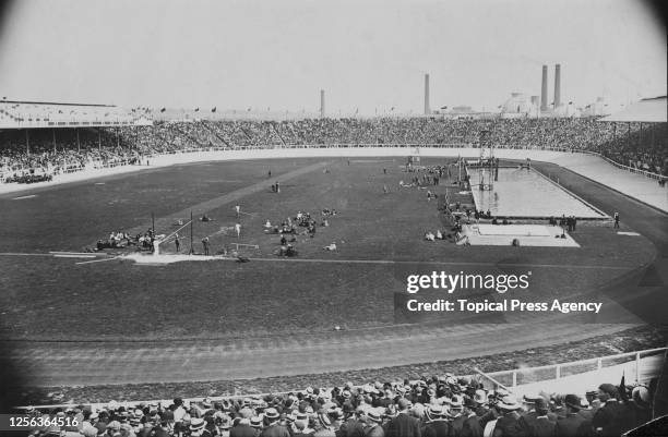 General view showing figures on the field of play beside the swimming pool at White City Stadium, built for the 1908 Summer Olympics, with crowds of...