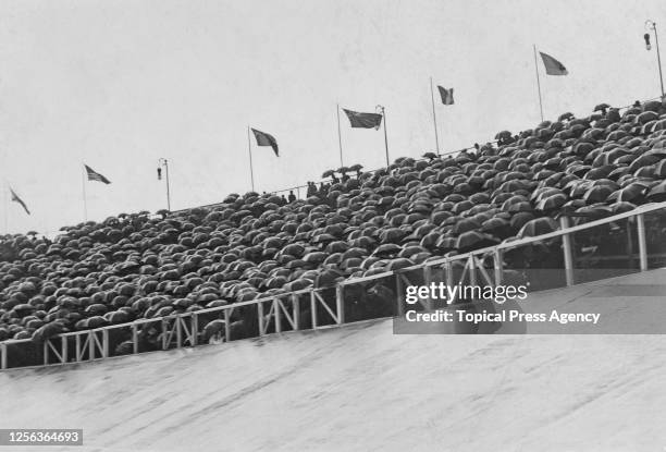 Spectators form a testudo as they shelter beneath umbrellas as rain falls on the 1908 Summer Olympics at White City Stadium in London, England, 1908....