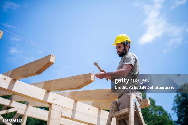 bouwvakkers die op houten dak van huis werken. - dakdekker stockfoto's en -beelden