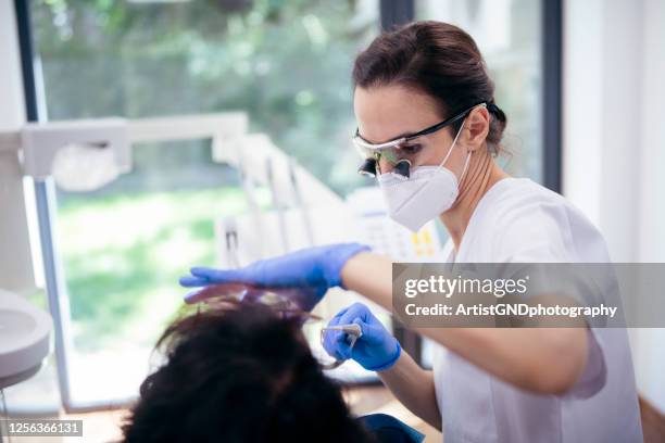 vrouwelijke tandarts die aan patiënt werkt. - wortelkanaal stockfoto's en -beelden