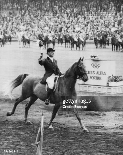 Swedish equestrian rider Hans Wilkne carries the Olympic torch into the Stockholm Olympic Stadium, which is hosting the equestrian events of the 1956...