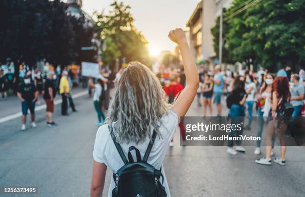 junge demonstrantin hebt die faust auf - ethnische zugehörigkeit stock-fotos und bilder