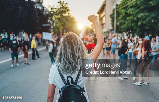 年輕女子抗議者舉起拳頭。 年輕女子抗議者舉起拳頭。