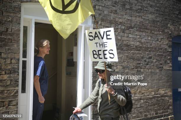 Local resident watches as a protester walks past with a sign saying 'Save the Bees' as they march through the city centre on May 20, 2023 in Bury St...
