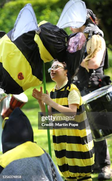 Young protester joins others, dressed in a bee costume and carrying a large model bee on a pole before marching into the city centre on May 20, 2023...