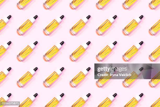 pattern made of glass bottle of oil with a pipette or face serum on a pastel pink background. - cbd oil stock pictures, royalty-free photos & images