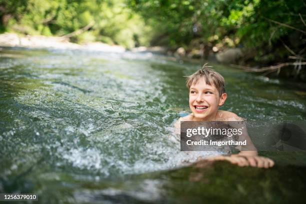little boy enjoying swimming in cold mountain river - tide rivers stock pictures, royalty-free photos & images