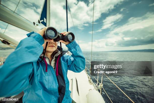 vrouw die door verrekijkers kijkt - verrekijker stockfoto's en -beelden