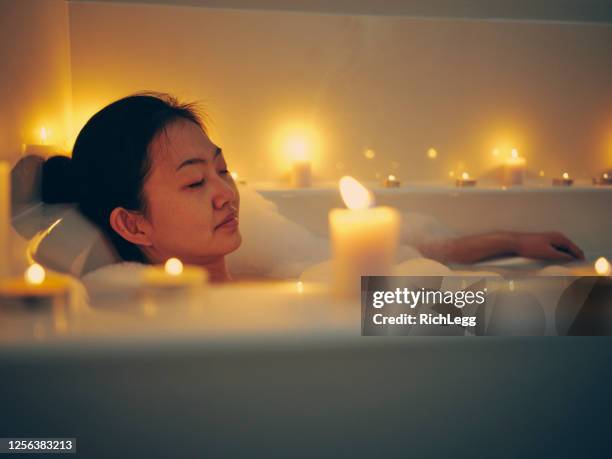 japanse vrouw die een bad van het kaarslicht neemt - bathroom night stockfoto's en -beelden