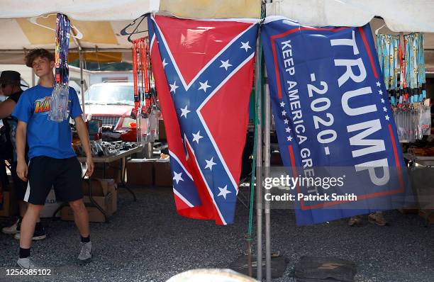 Vendor displays a confederate and Trump 2020 "Make America Great Again!" flag outside of the Bristol Motor Speedway prior to the NASCAR Cup Series...