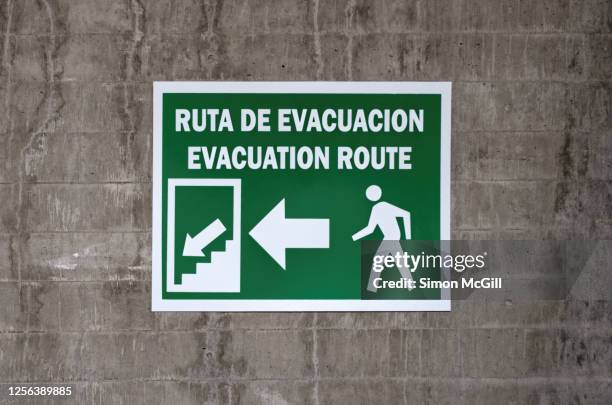 bilingual spanish & english language 'ruta de evacuación/ evacuation route' sign on a concrete wall - evacuation plan stock pictures, royalty-free photos & images