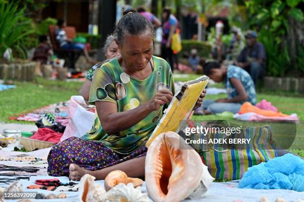 Papua New Guinean women sell souvenirs at a craft market in Port Moresby on May 20, 2023.