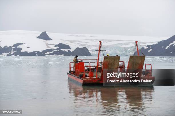 Brazilian Navy officers maneuvering the cargo vessel to unload containers from the Ary Rongel Polar Ship with the Nunatak Tern in the background, on...