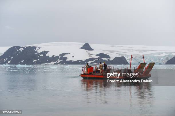 Brazilian Navy officers maneuvering the cargo vessel to unload containers from the Ary Rongel Polar Ship with the Nunatak Tern in the background, on...