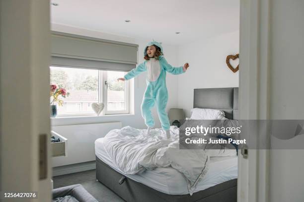 young girl jumping on parents' bed - double bed stock pictures, royalty-free photos & images