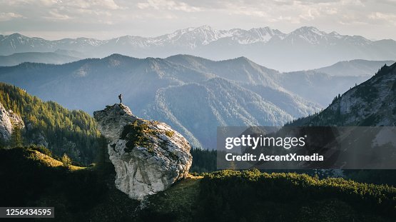 Hiker relaxes on mountain ridge at sunrise Hiker relaxes on mountain ridge at sunrise