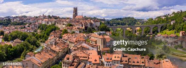 aerial views of the rooftops, landmarks, river and bridges of the old town of fribourg in switzerland. - freiburg skyline stock pictures, royalty-free photos & images