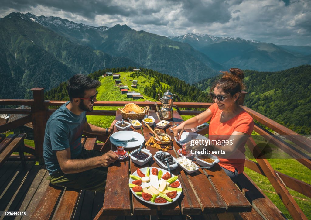 Young couple having breakfast with landscape view in Pokut Plateau, Camlıhemsin, Rize, Black Sea Region of Turkey