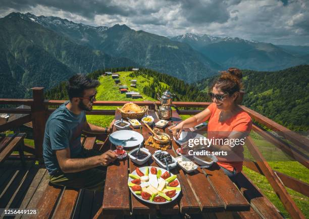 young couple having breakfast with landscape view in pokut plateau, camlıhemsin, rize, black sea region of turkey - cheddar village stock pictures, royalty-free photos & images