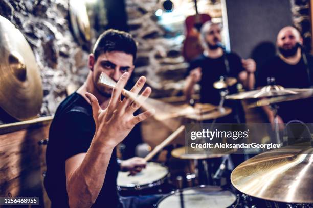 drummer mostrando trucos de spinning de palo mientras graba con banda - heavy metal fotografías e imágenes de stock