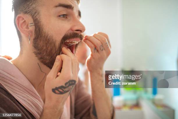 nahaufnahme des mannes, der zähne mit zahnseide reinigt - zahnseide stock-fotos und bilder