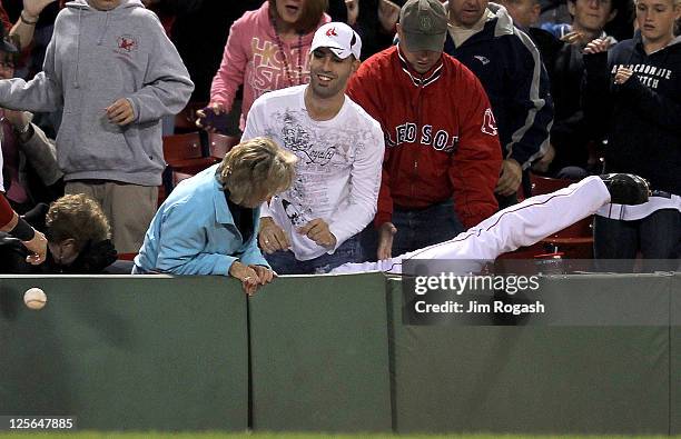 Conor Jackson of the Boston Red Sox, seen falling in the stands, attempts to catch a foul ball in the first inning in the second game of a...