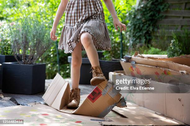 child (6-7) trying to flatten cardboard boxes by stamping on them with her feet - crush foot stock pictures, royalty-free photos & images