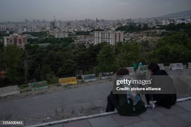 May 2023, Iran, Teheran: Two women sit at sunset in the east of the metropolis with a view of the skyline. Photo: Arne Bänsch/dpa