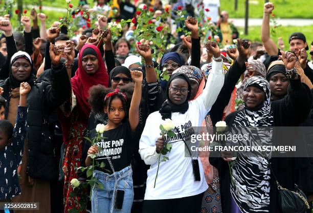 Assetou Cisse , her daughter , her mother and attendees hold their fists in the air during a day of tribute to her brother Mahamadou Cisse, killed by...