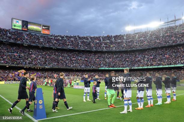 Real Sociedad's players form a guard of honour as Barcelona's players enter the pitch before the start of the Spanish league football match between...