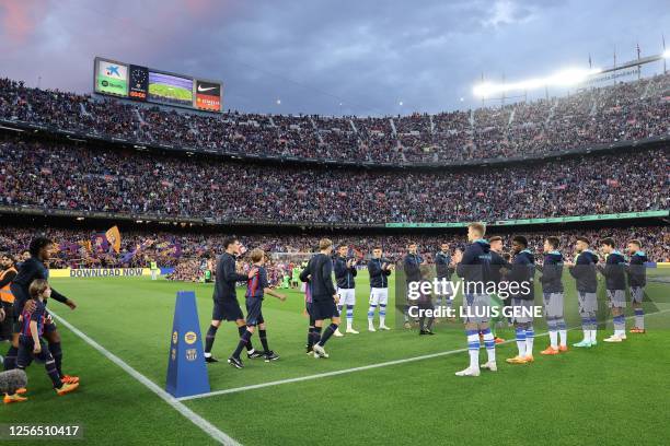 Real Sociedad's players form a guard of honour as Barcelona's players enter the pitch before the start of the Spanish league football match between...